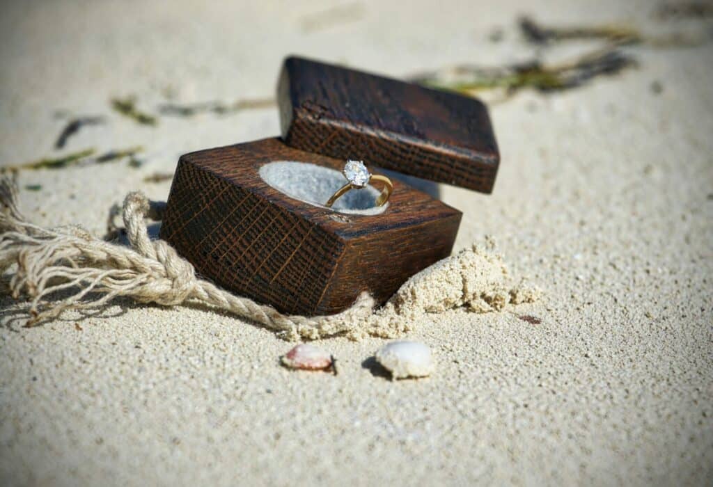 minimalist engagement ring in brown box on sand 