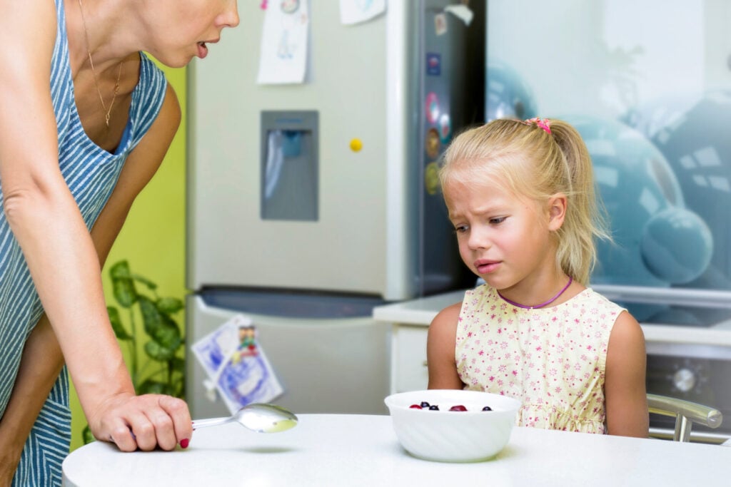 girl upset at dinner table and being told of by mother about picky eating 