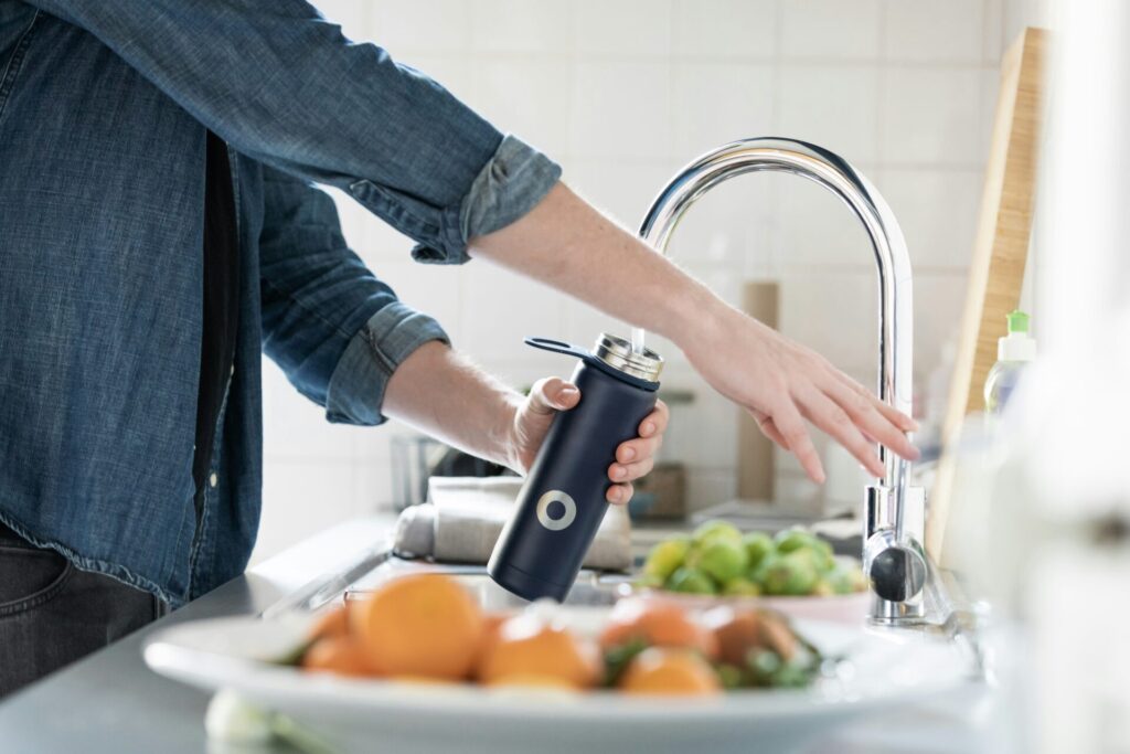 man refilling reusable water bottle 