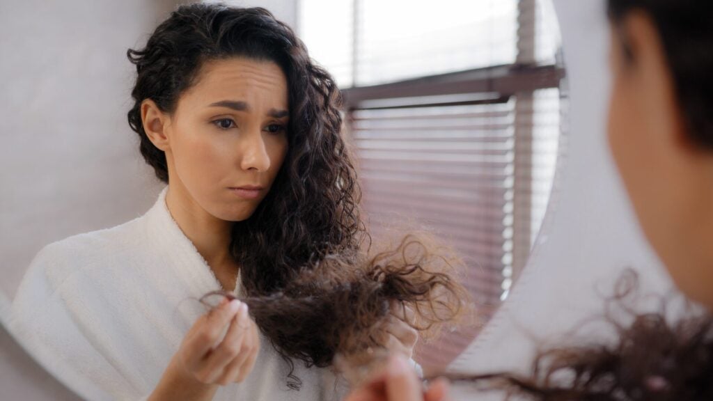 woman looking frustrated at her damaged hair 