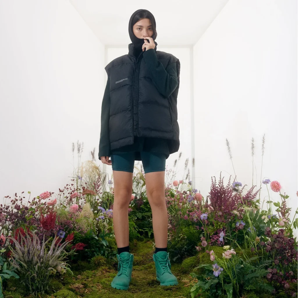 woman with Pangaia coat on surrounded by wildflowers 