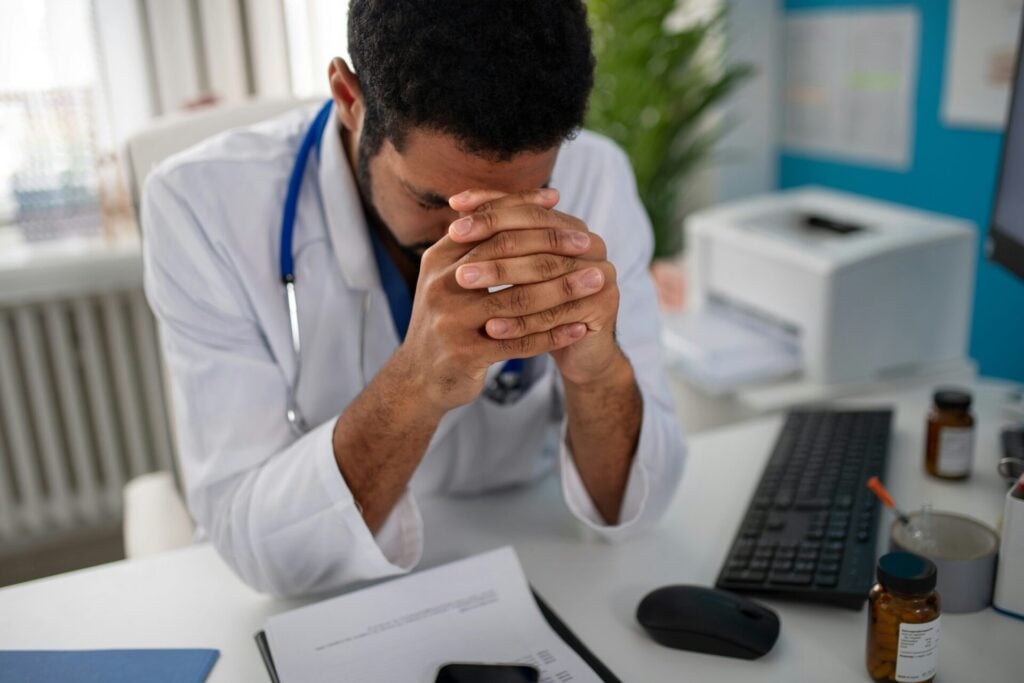 stressed young doctor with head in hands