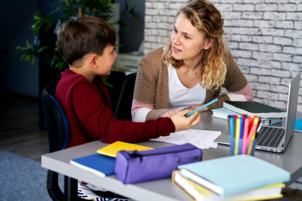 teacher and young student at a desk in a classroom