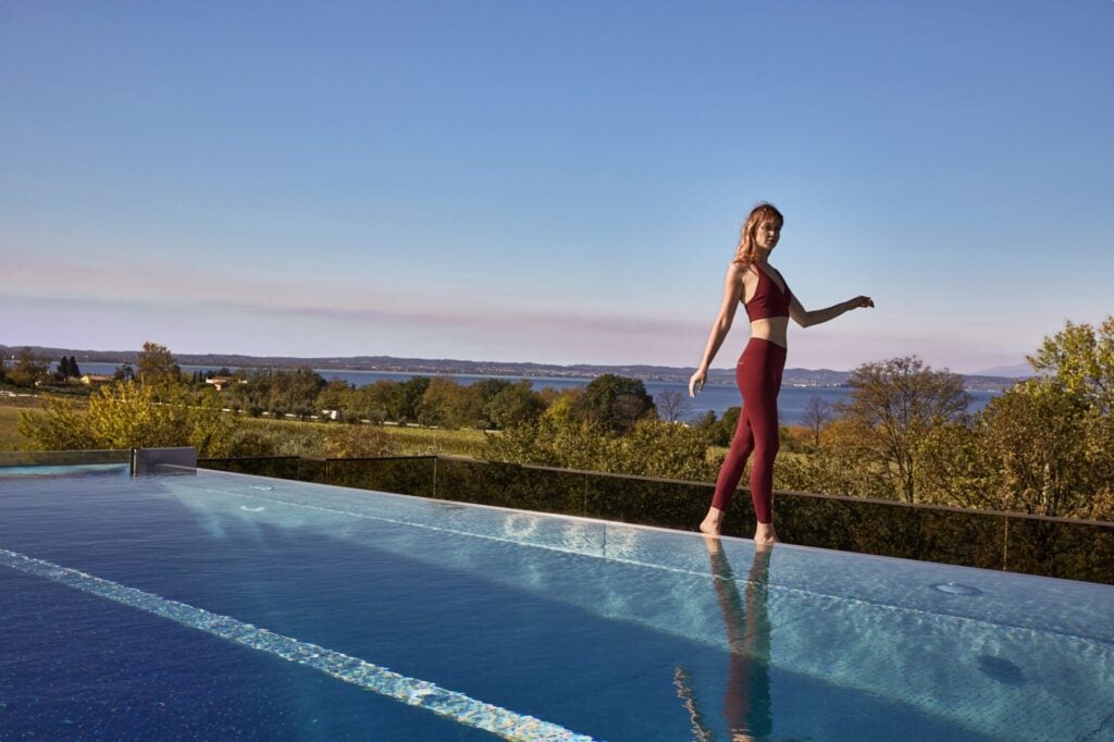 Woman wearing plant-based activewear on the edge of a swimming pool 