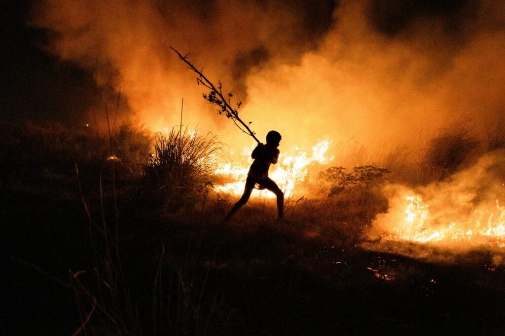 boy putting out wildfire emphasising the fact that half the world's children face climate crisis risks