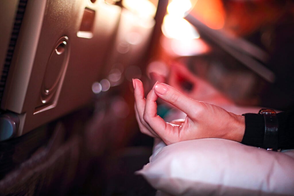 A person in airplane with travel anxiety  being afraid while sitting in an aeroplane seat and doing yoga to relax