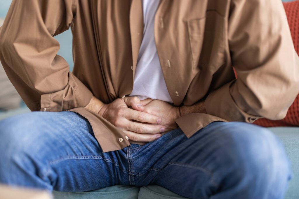 Man holding stomach with hands, feeling discomfort and pain