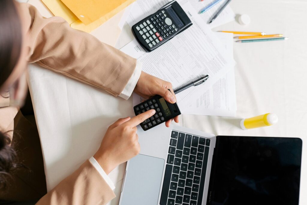 Woman's hand budgeting with calculator and laptop