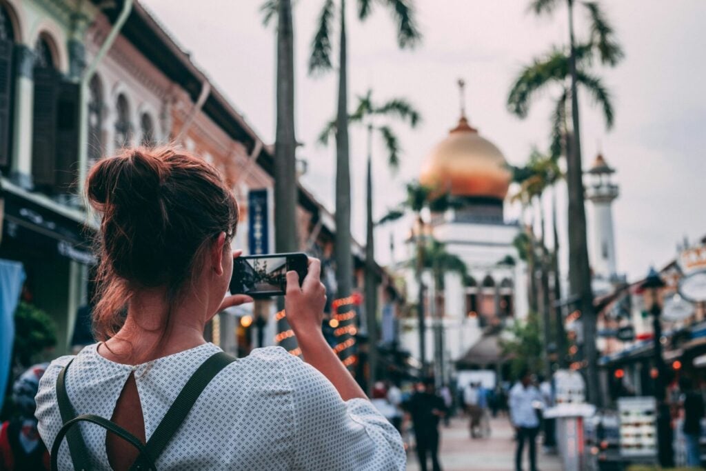 woman taking photograph while on holiday - one of the travel etiquette rules