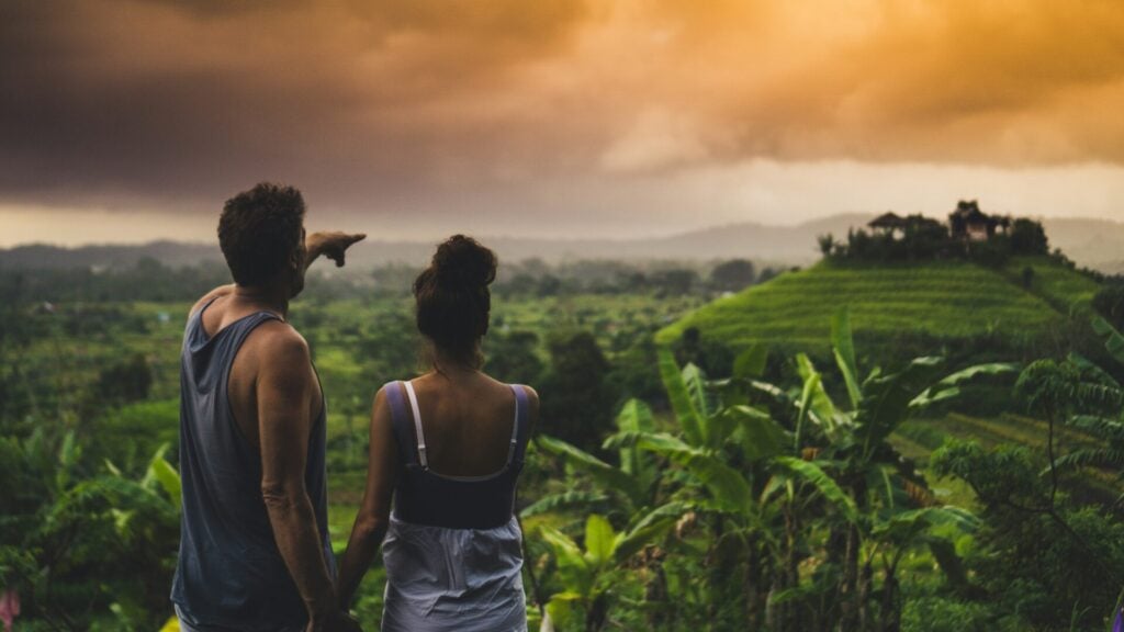 couple pointing over a leafy jungle canopy signifying an eco-holiday romance 