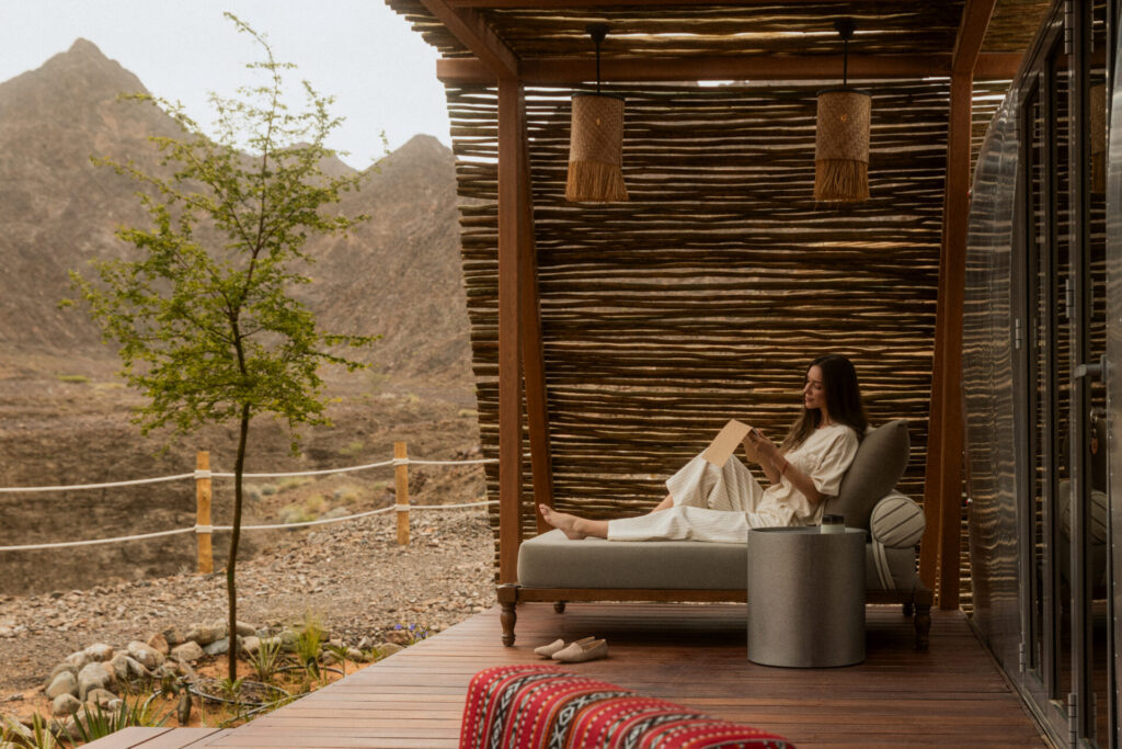 Woman reading on terrace at Caravan Hatta by Our Habitas