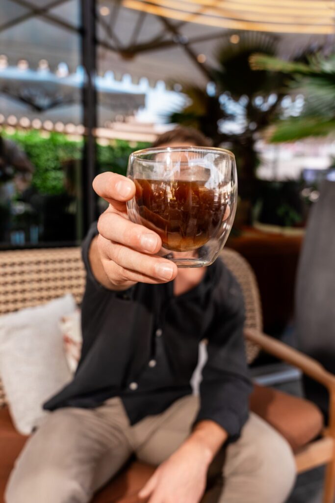 Man holding shot of coffee to camera 